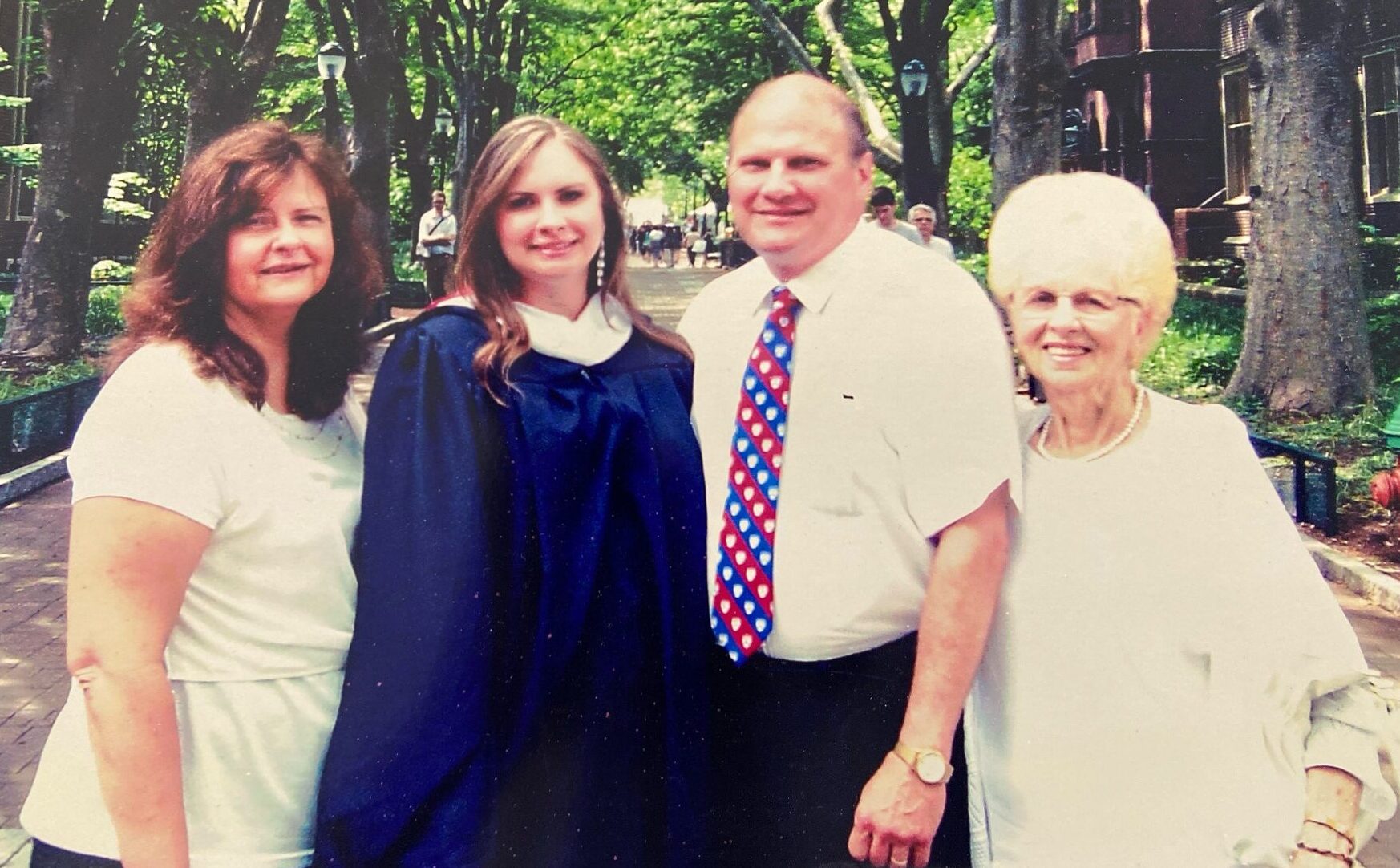 Photo of four people with one person in graduation gown.