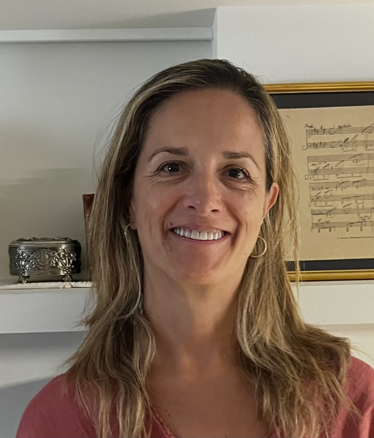 Photo of Carmen Rodriguez in front of a wall with framed items.