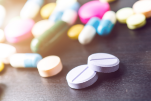 Brightly colored pills strewn across a dark table at an angle