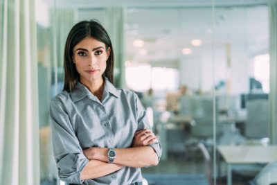 Woman standing in an office, leaning against glass wall